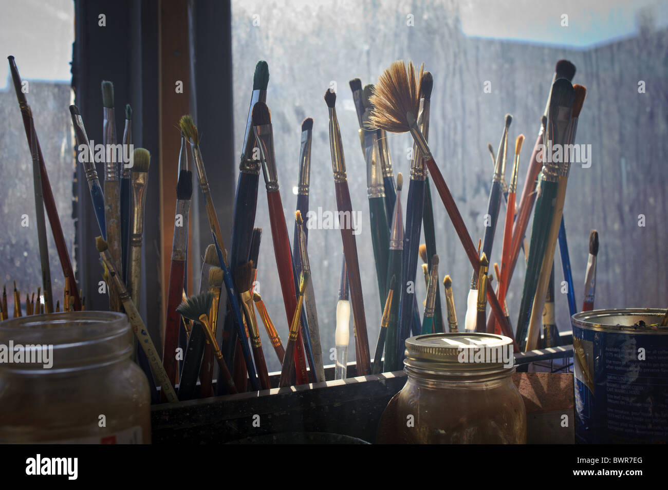 Artist paint brushed against window in artist studio Stock Photo