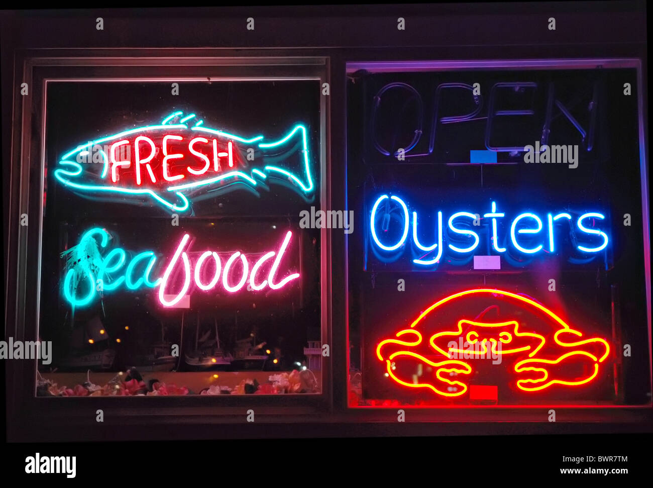 Nighttime window filled with a variety of seafood neon signs Stock Photo