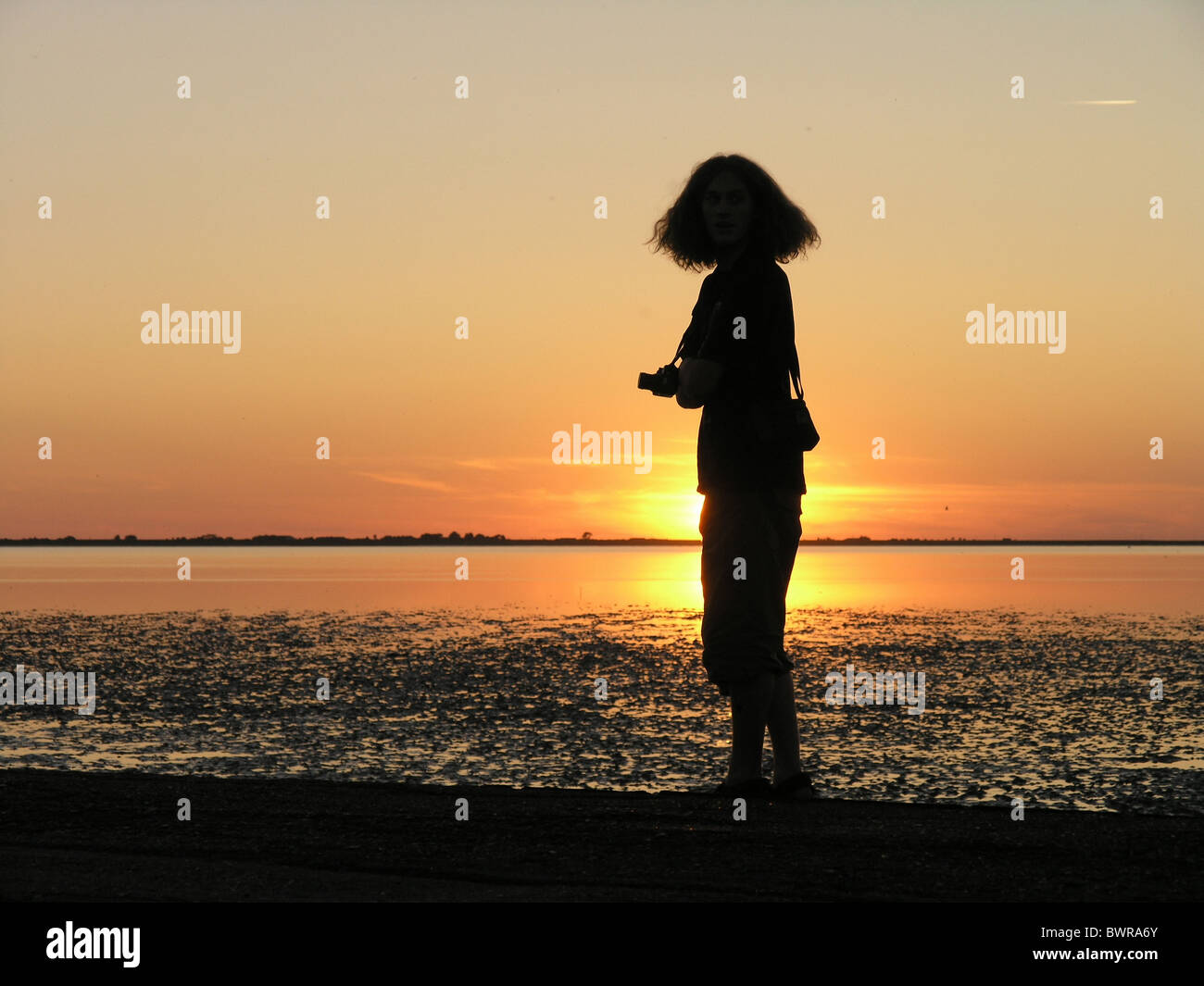 Man person photographer photo camera standing coast sea lake bank sunset sunrise silhouette outlines lan Stock Photo