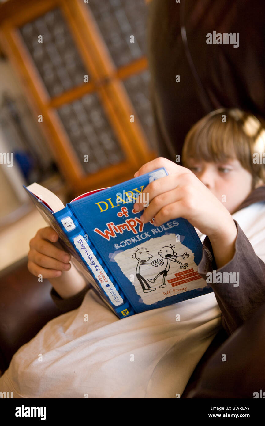 Eight year old child reading a popular American novel, Diary of a Wimpy Kid Stock Photo