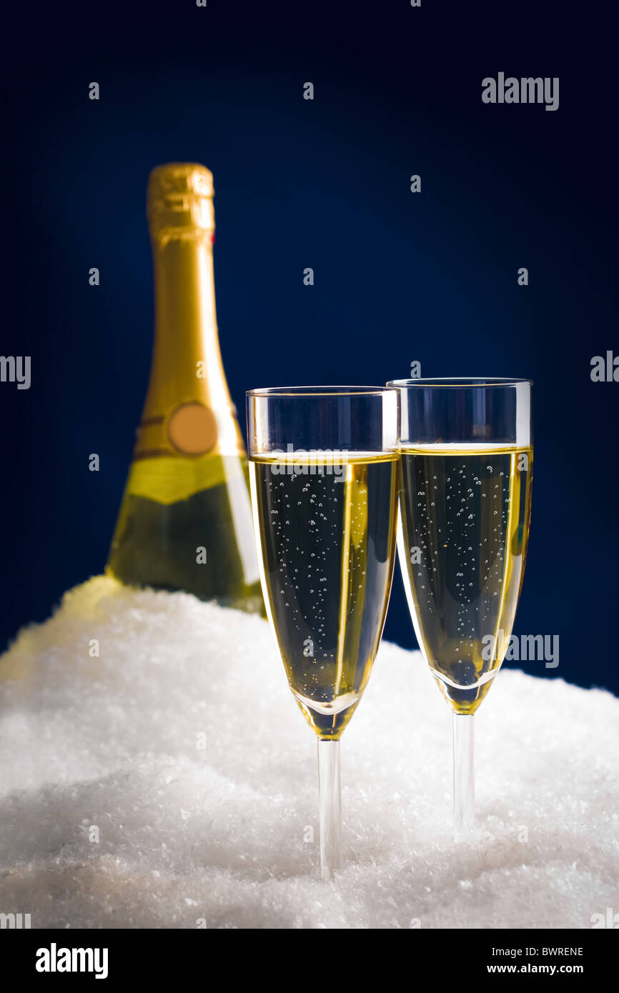 Vertical photo of two champagnes with bottle at background in snow Stock Photo