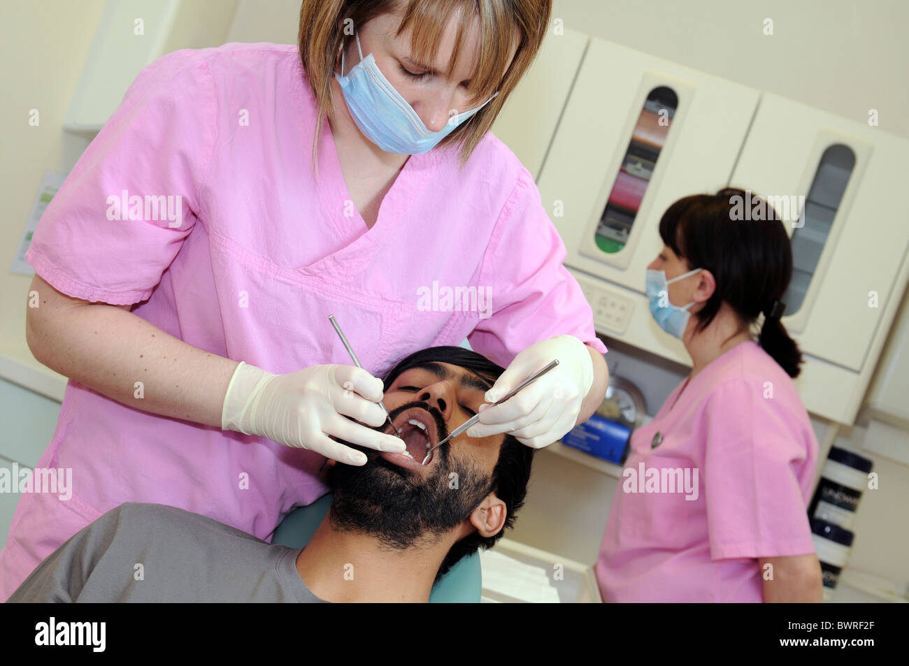 An asian male patient having a teeth examination by a female dentist in