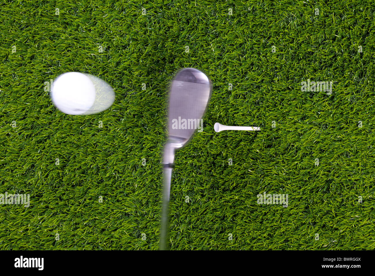 Photo of an iron hitting a golf ball off the tee with motion blur on the club and ball. Actual shot not photoshopped in. Stock Photo