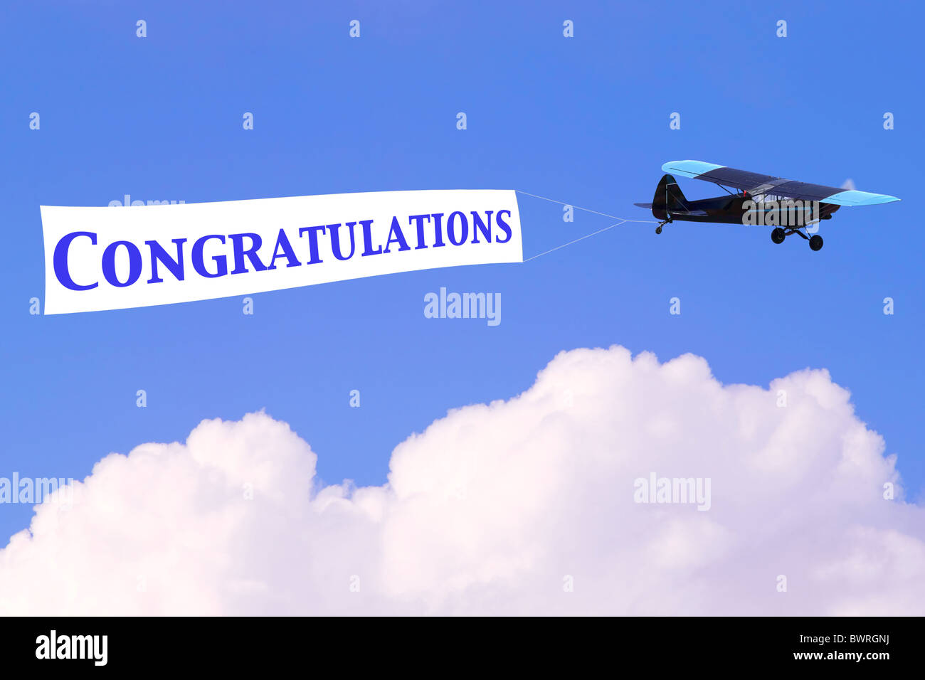 An airplane towing a banner with the word Congratulations in blue, good for male related themes or birth of a baby boy Stock Photo
