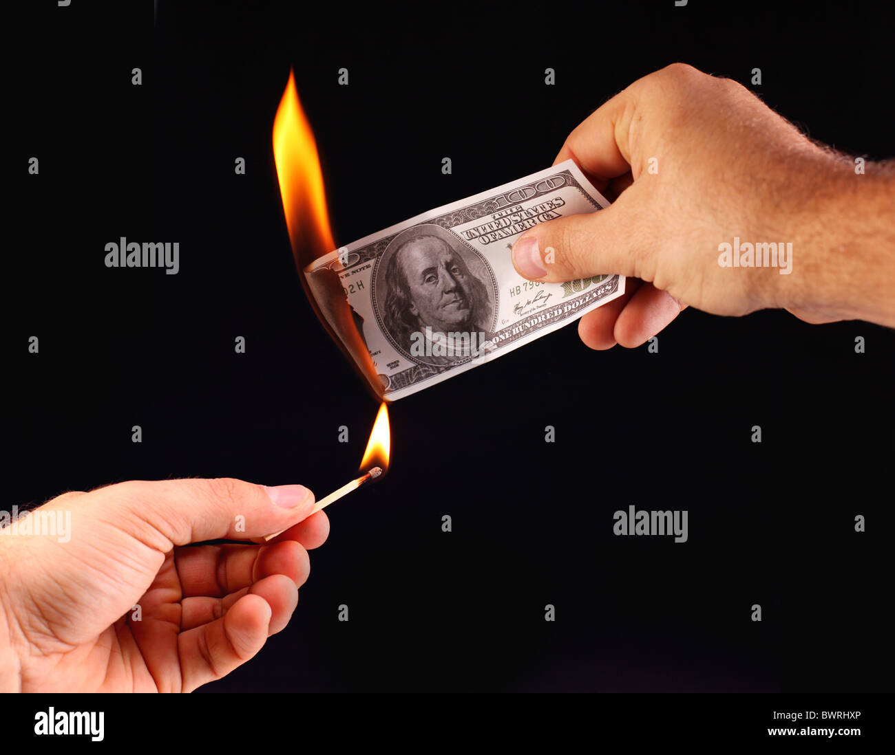 $ 100 in hand, set fire to a match. Isolated on a black Stock Photo