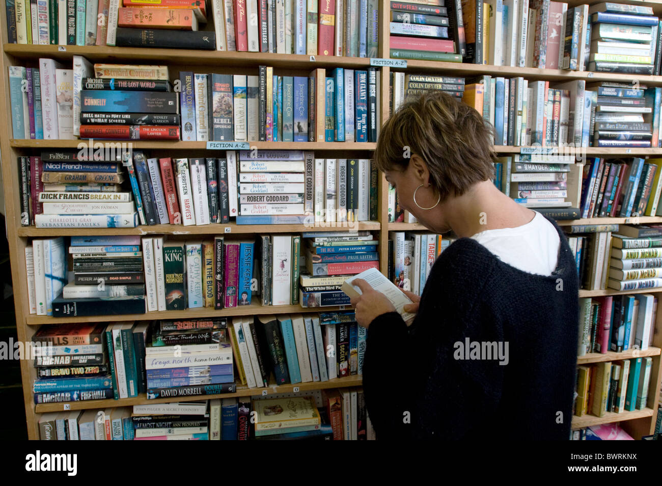A woman browses a second-hand bookshop in Falmouth, UK Stock Photo