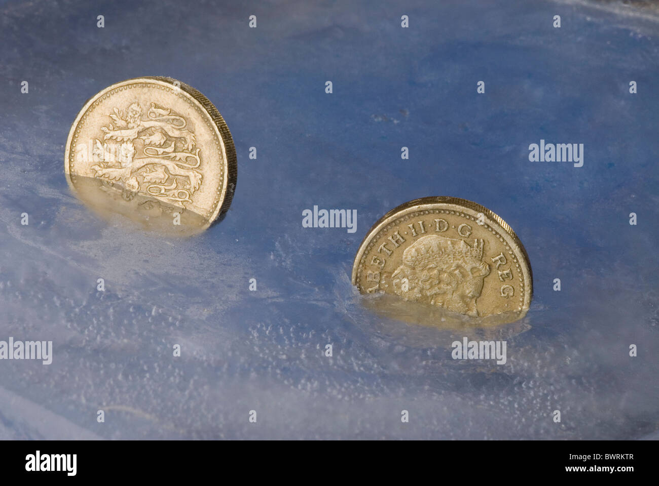 Frozen pound - coins suspended in ice economy Stock Photo