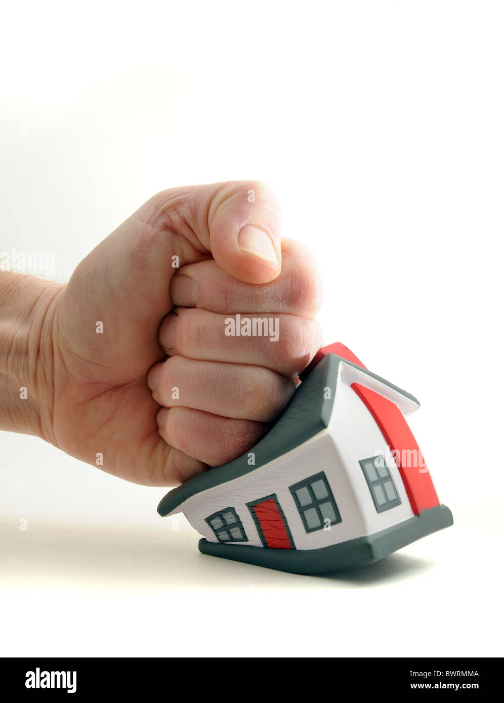 HOUSE BEING SQUASHED/HIT BY MANS FIST RE HOUSING MARKET,PRICES,HOUSEHOLD BUDGETS ETC. UK Stock Photo