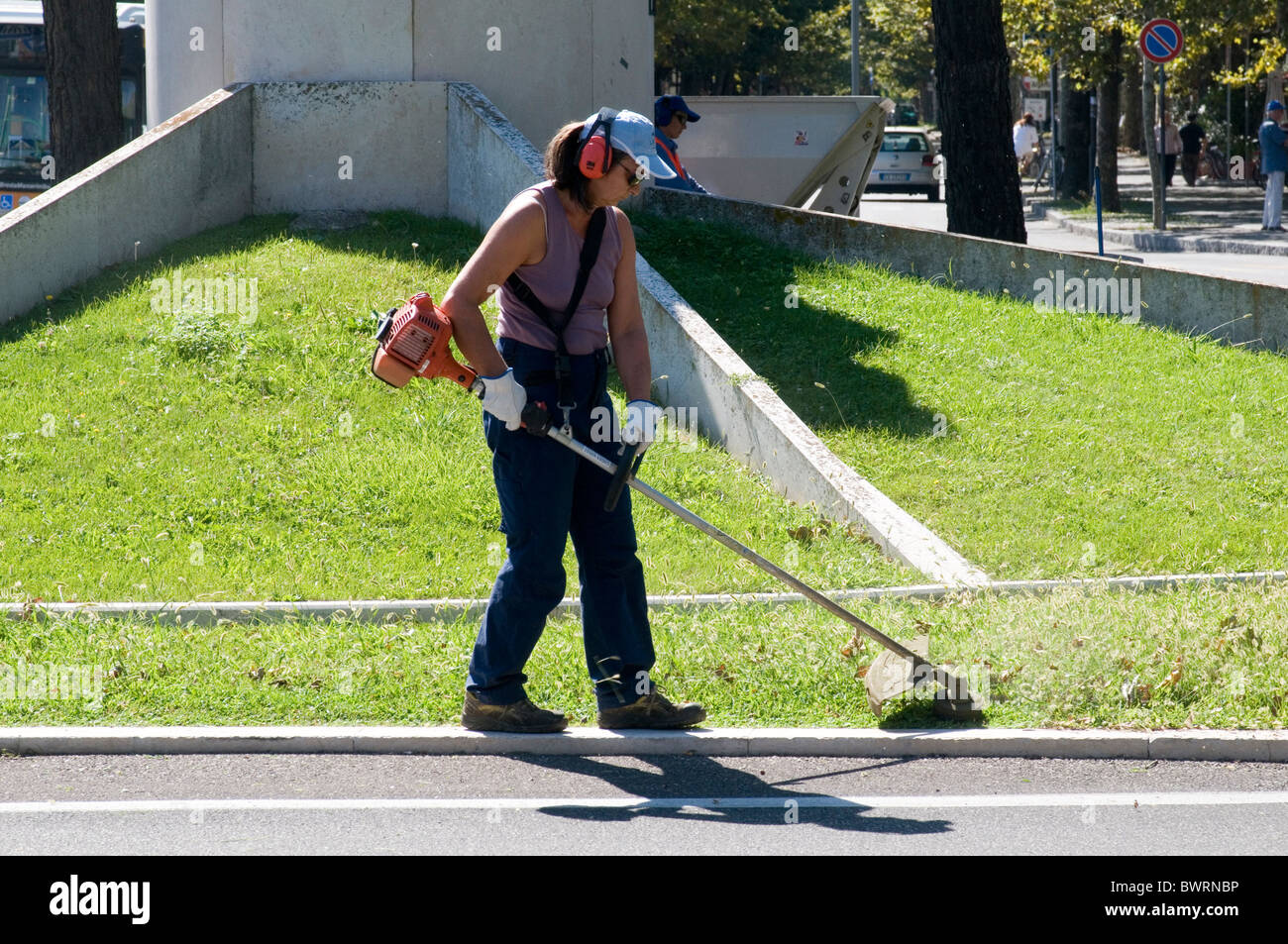 strimmer strimmers strimming gardener gardening cutting grass tidying tidy trim trimming municipal worker council contractor ear Stock Photo