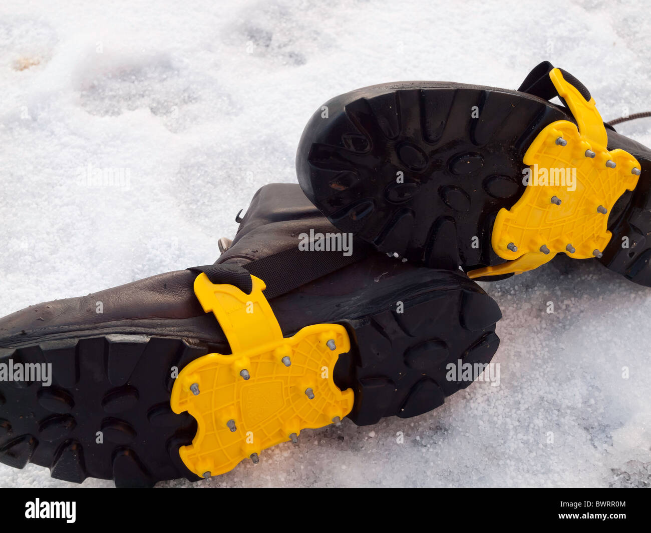 Soles of a pair of Mens walking boots with crampons fitted for safety