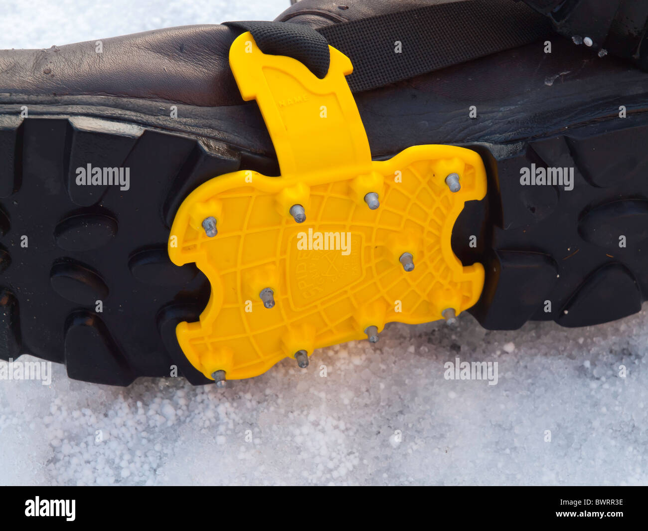 Sole of a mans walking boot with crampon fitted for safety on slippery