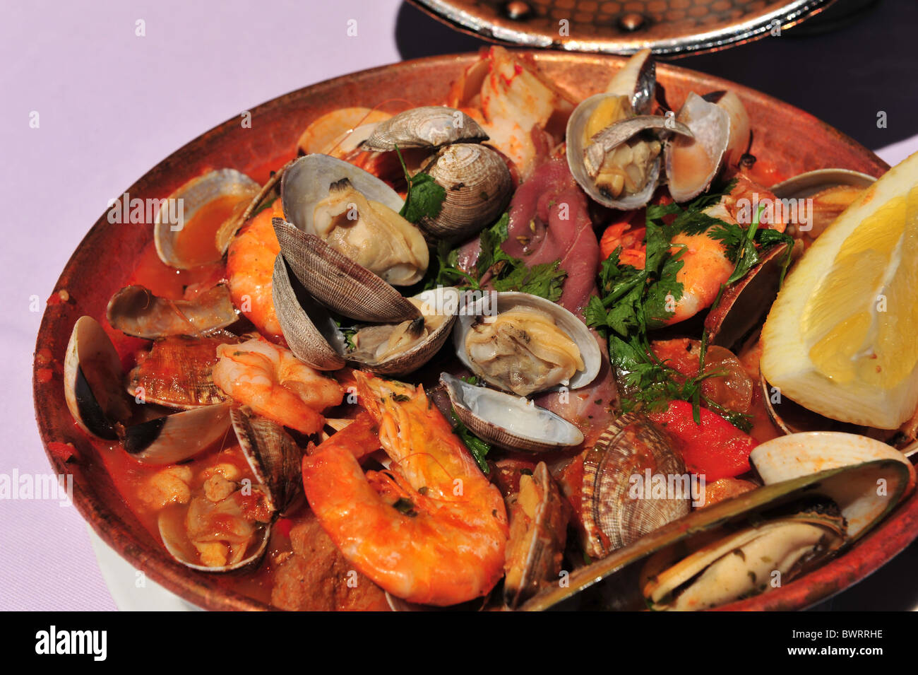 Seafood Cataplana cooked and served in a circular copper pot Stock
