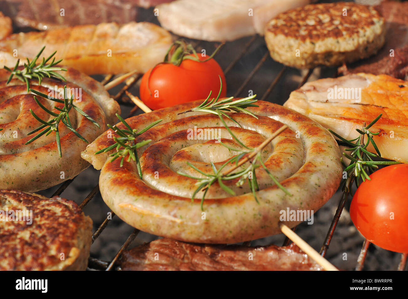 Spiral Cumberland sausages and other meat items being grilled outdoors