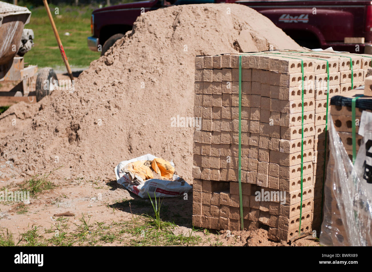 A pile of sand and a stack of bricks are piled up for new home construction. Stock Photo