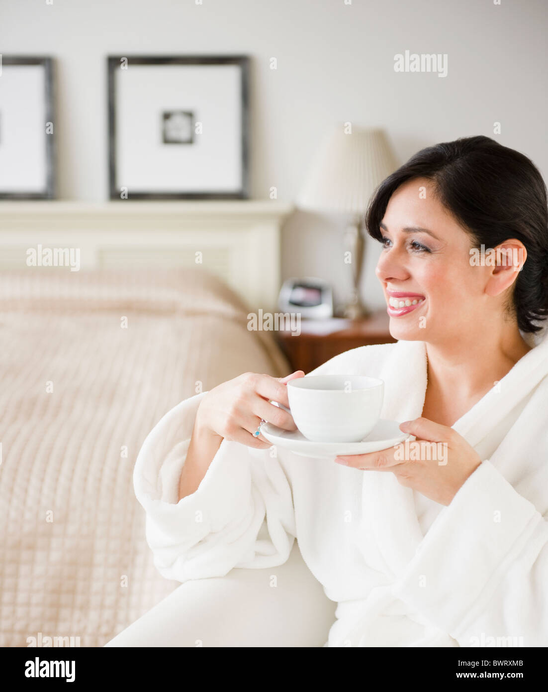 Hispanic woman in bathrobe drinking coffee in bedroom Stock Photo Alamy