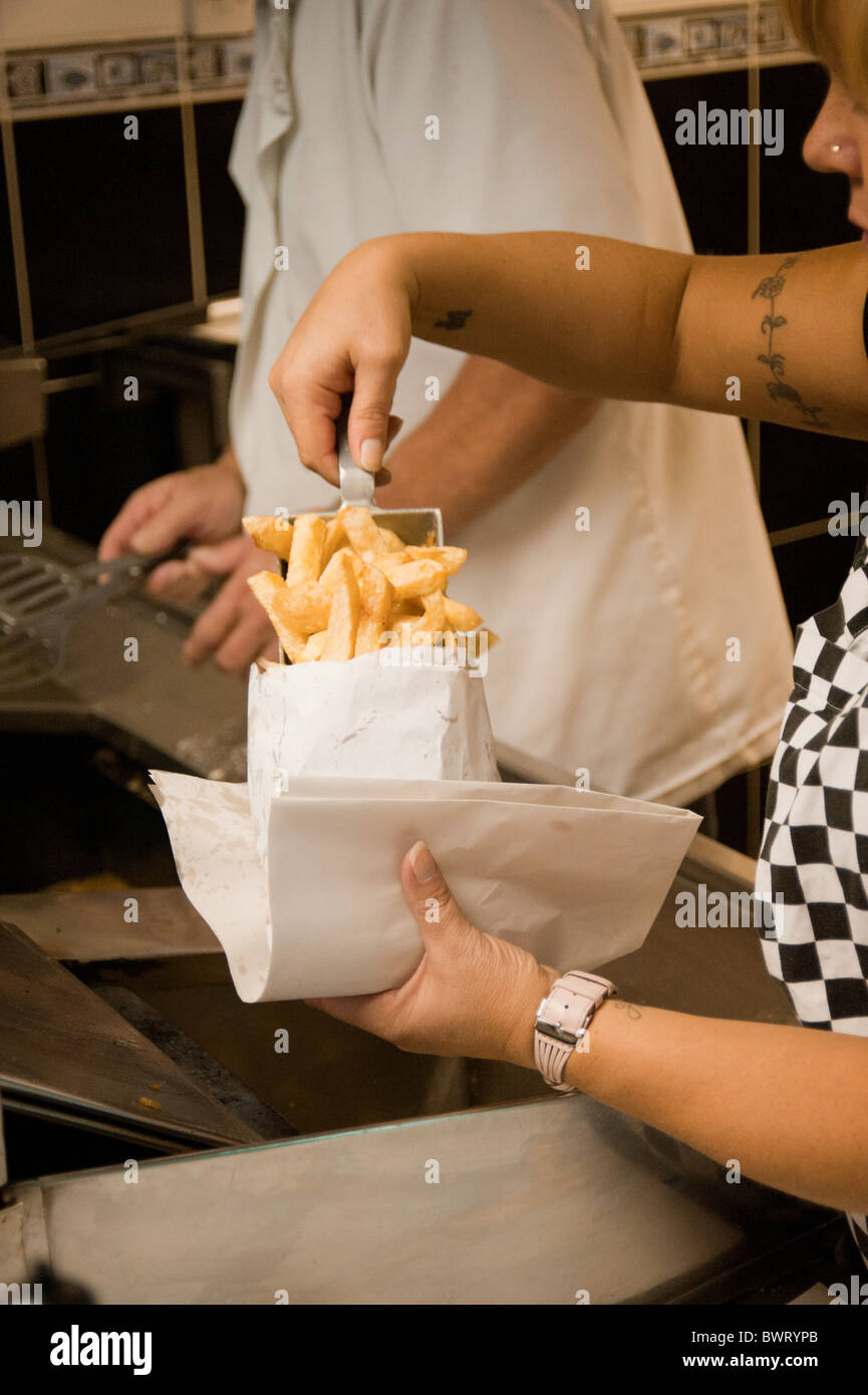 In a traditional fish and chip shop, a portion of chips are scooped