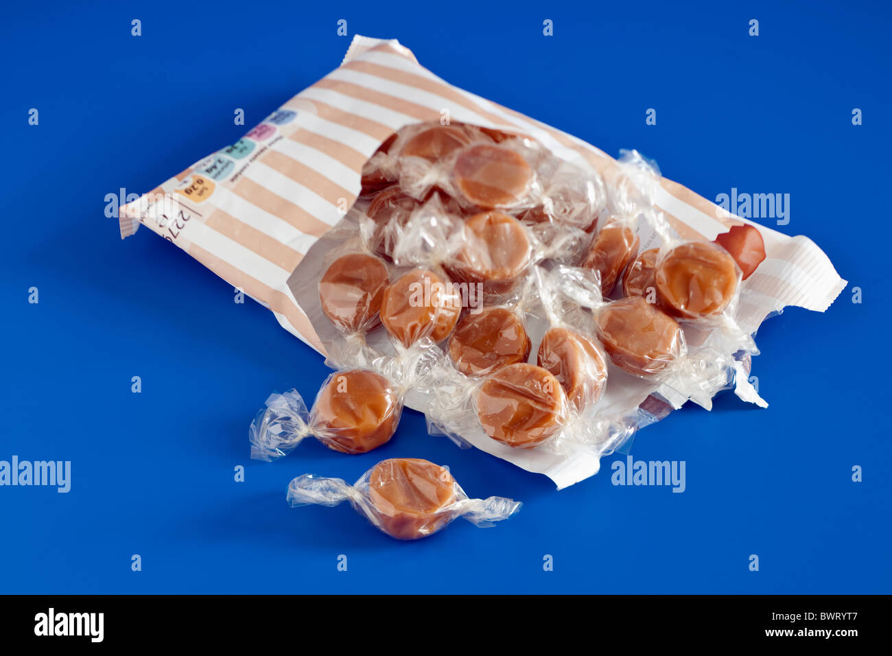 Torn open bag of clear cellophane wrapped toffee sweets Stock Photo