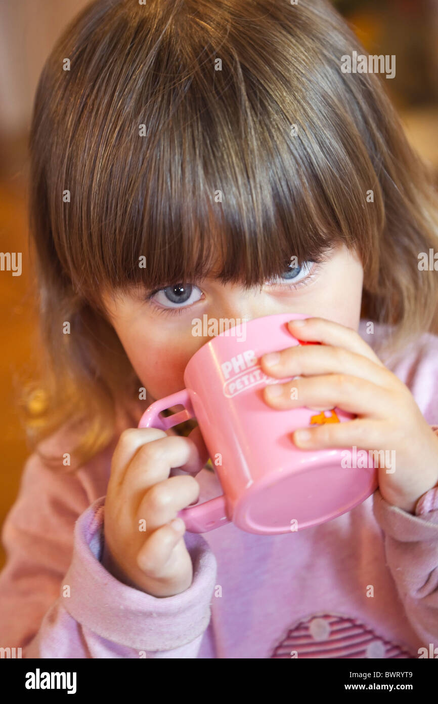 Two and a half year old girl toddler drinking from plastic cup Stock Photo