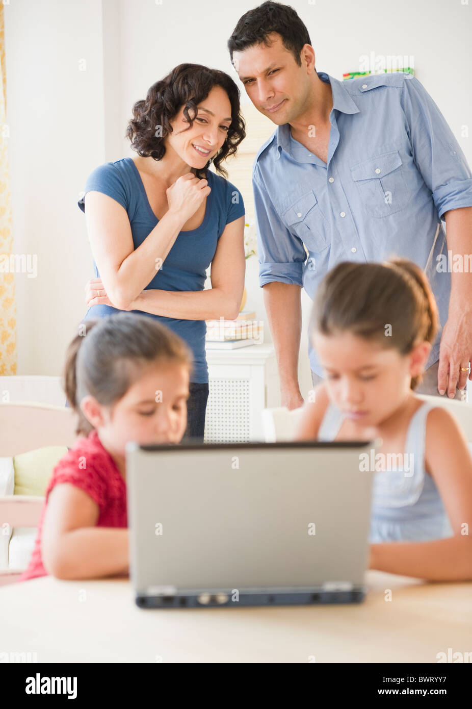 Father and mother watching children using internet together Stock Photo