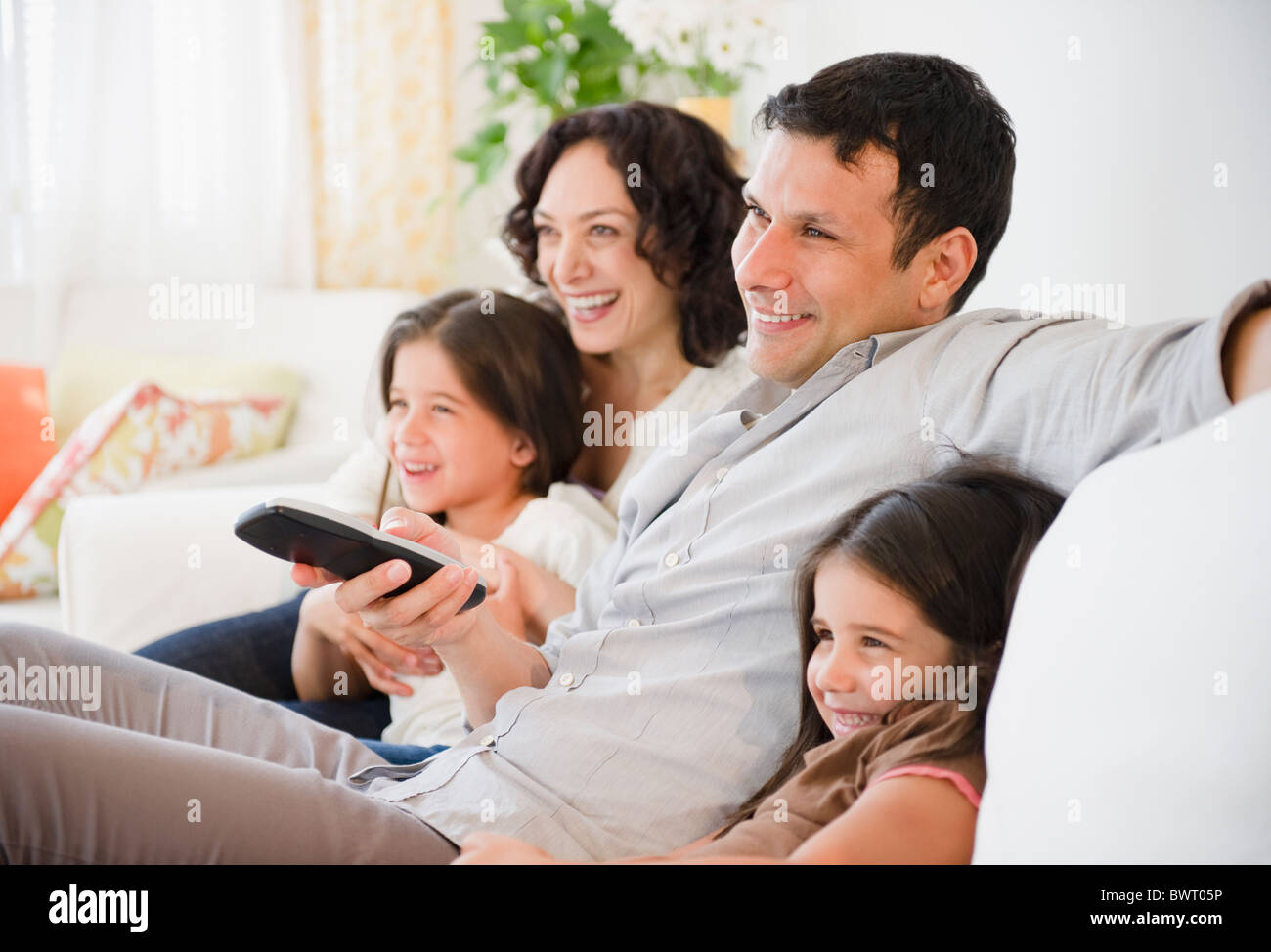 Happy family sitting on sofa watching television Stock Photo