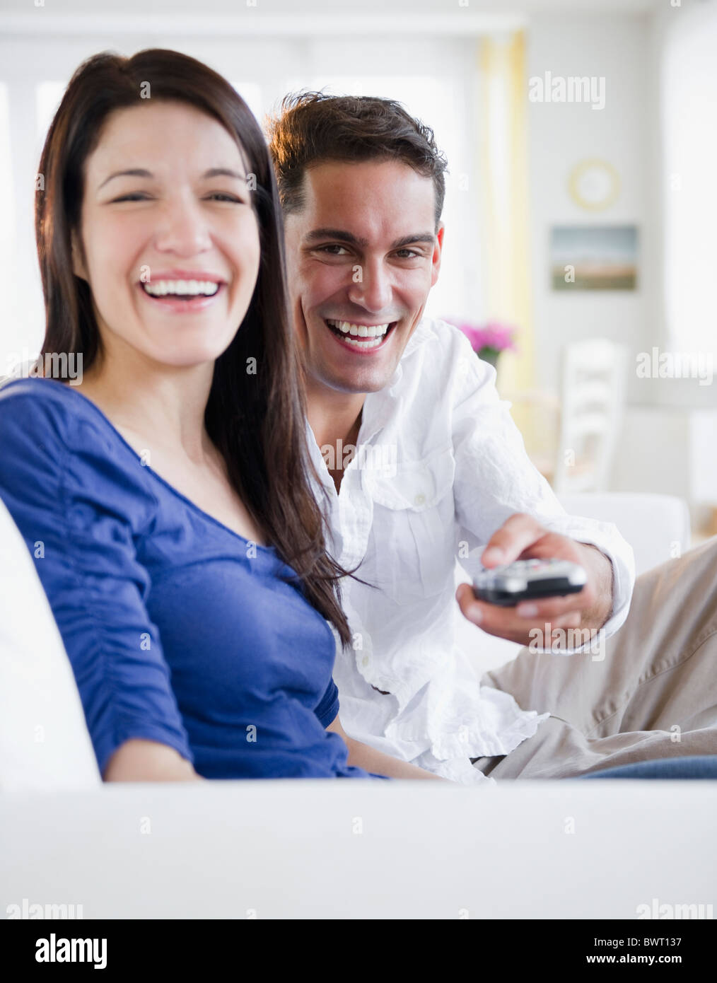 Mixed race man with remote control watching television with wife Stock Photo