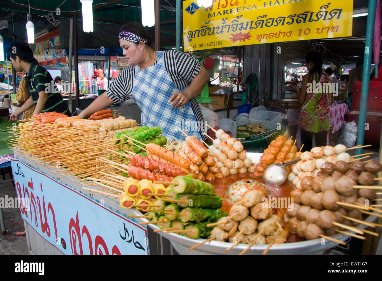 Woman vendor selling skewered food on Phuket weekend market, Thailand Stock Photo