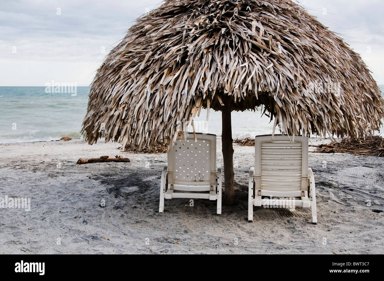Two plastic chaise lounge chairs under a palapa structure offer shade and privacy on Panama's Playa Blanca. Stock Photo