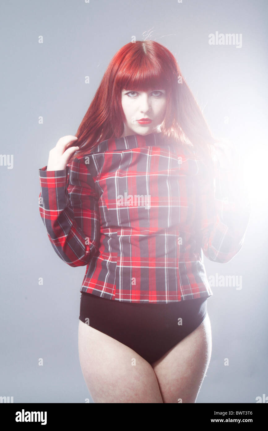 Fashion portrait of a young redhead model wearing a tartan jacket and leotard. Stock Photo