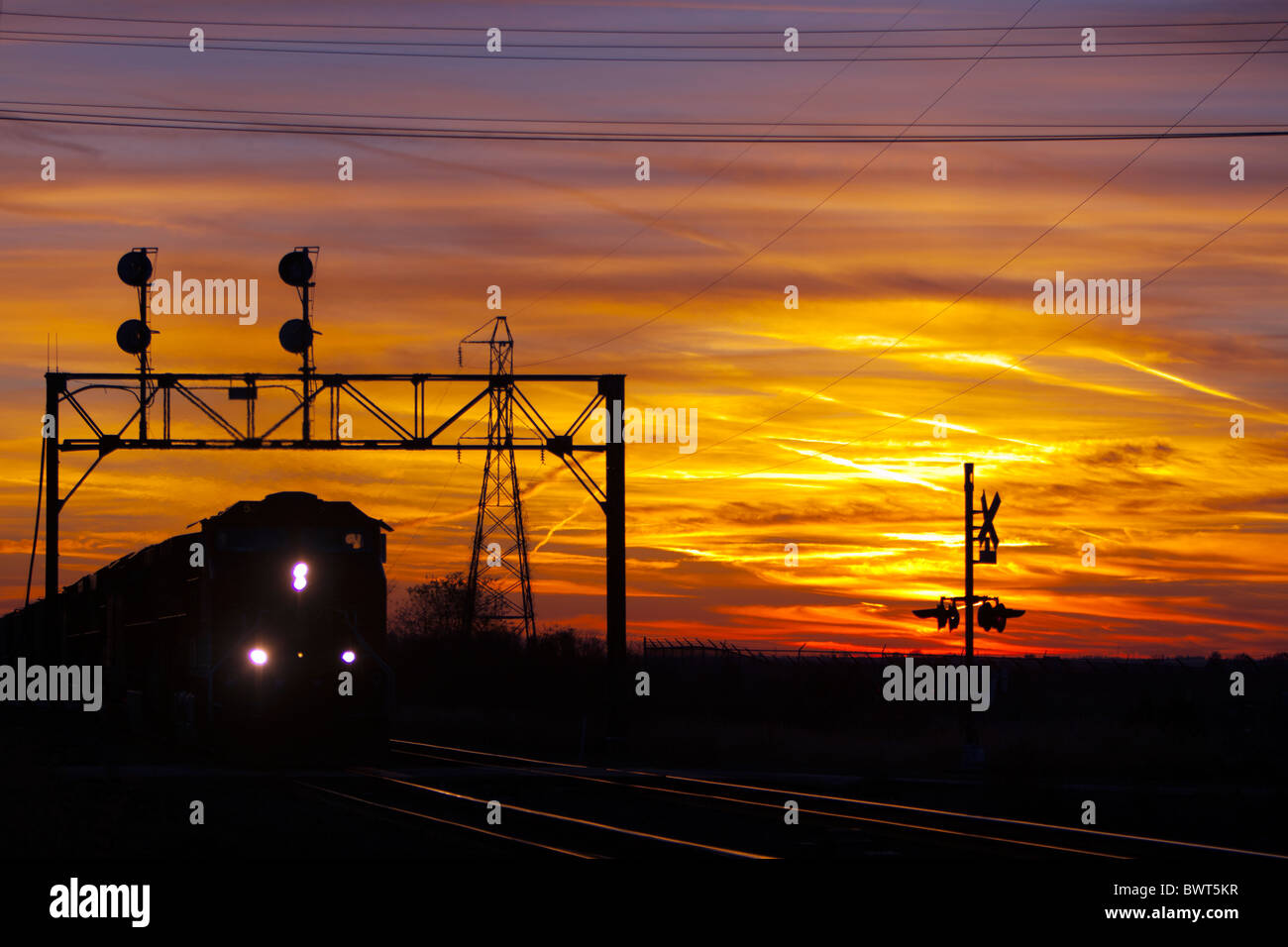 Freight train rolls out of a colorful sunset. Stock Photo