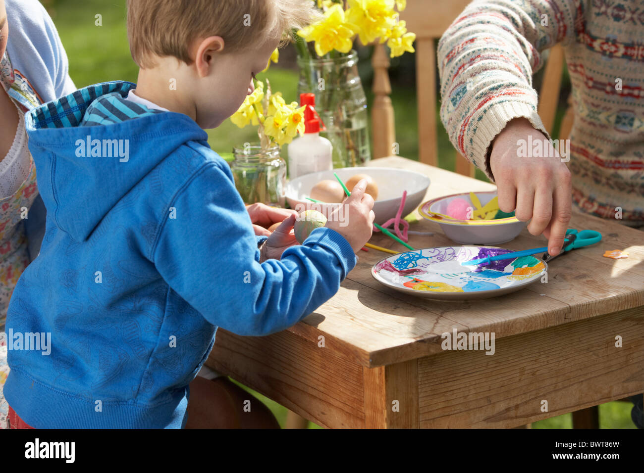 Father And Son Decorating Easter Eggs On Table Outdoors Stock Photo