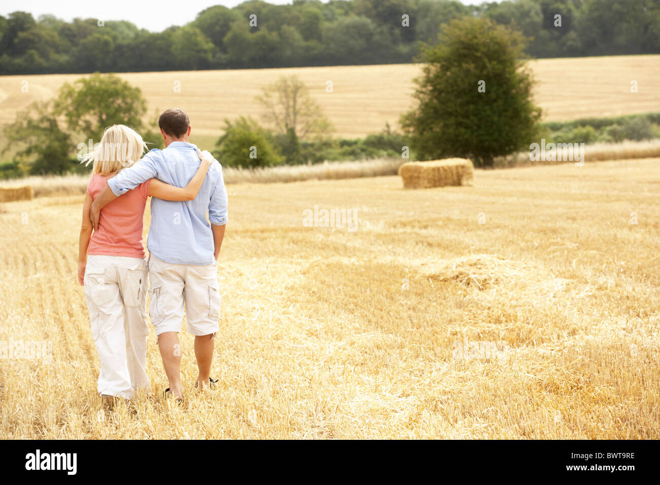 Couple Walking Together Through Summer Harvested Field Stock Photo