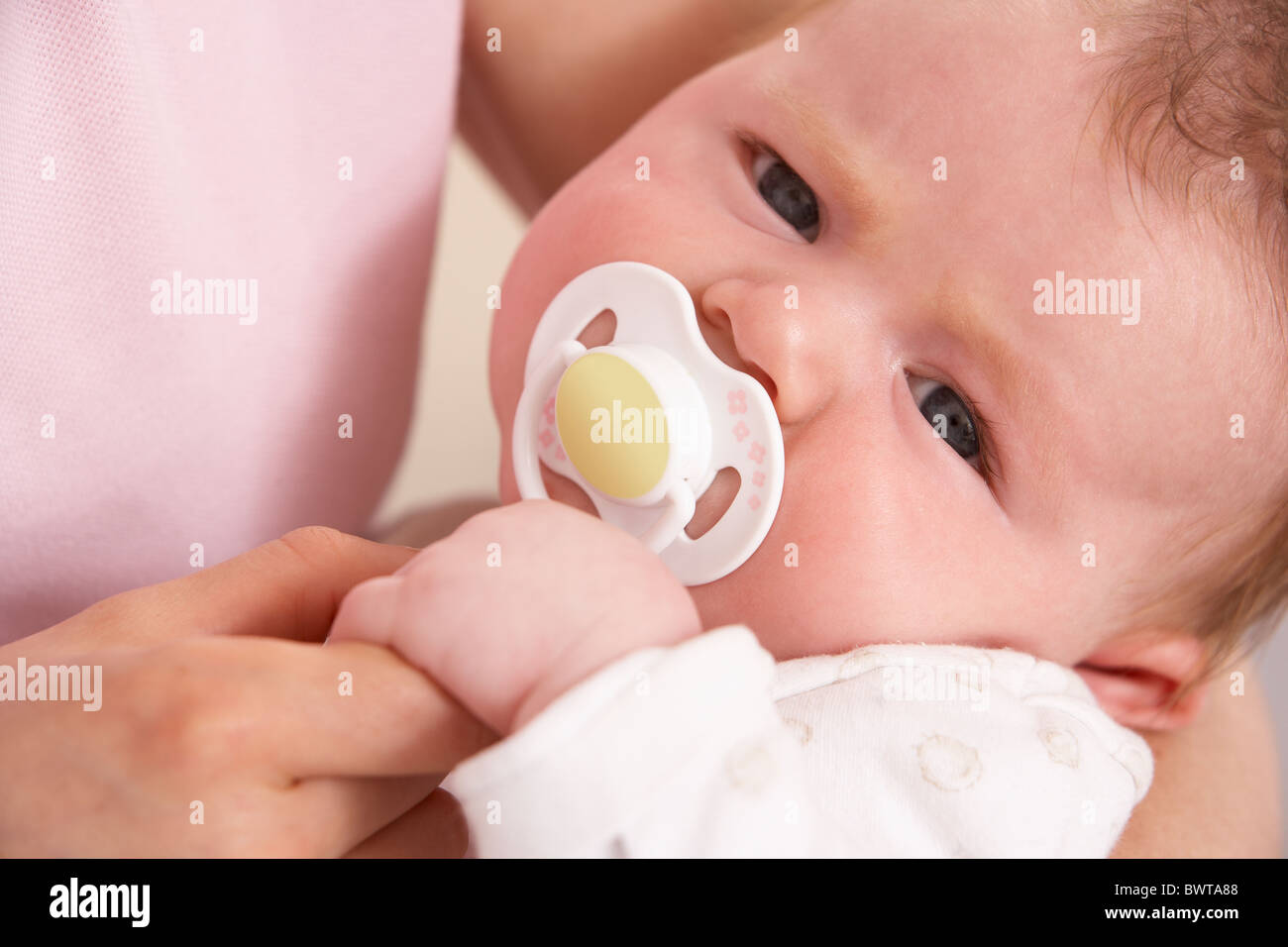 Close Up Of Baby Boy With Dummy Holding Mothers Hand Stock Photo