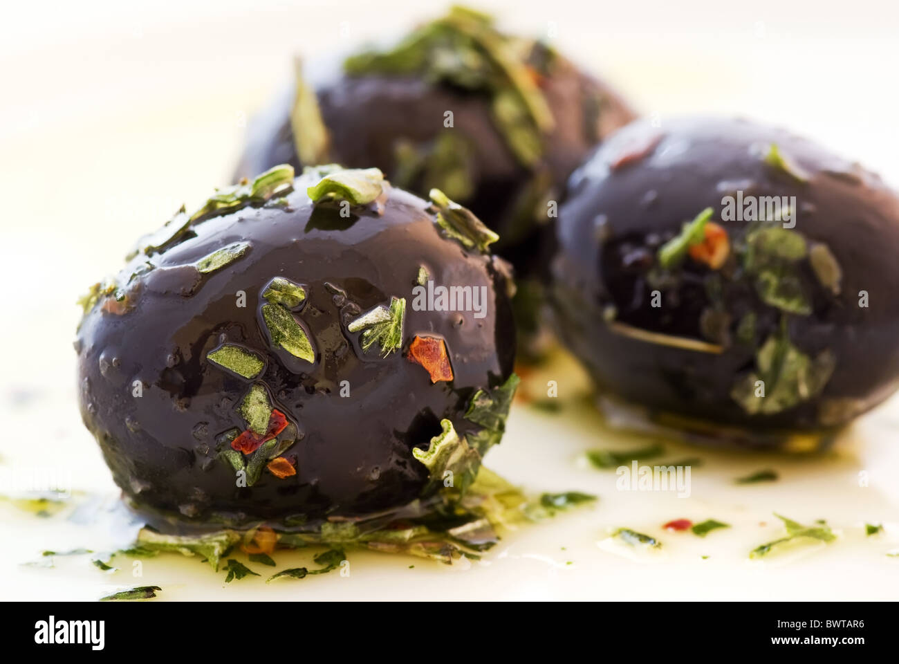 Pickled black olives with Italian herbs in olive oil as closeup on a