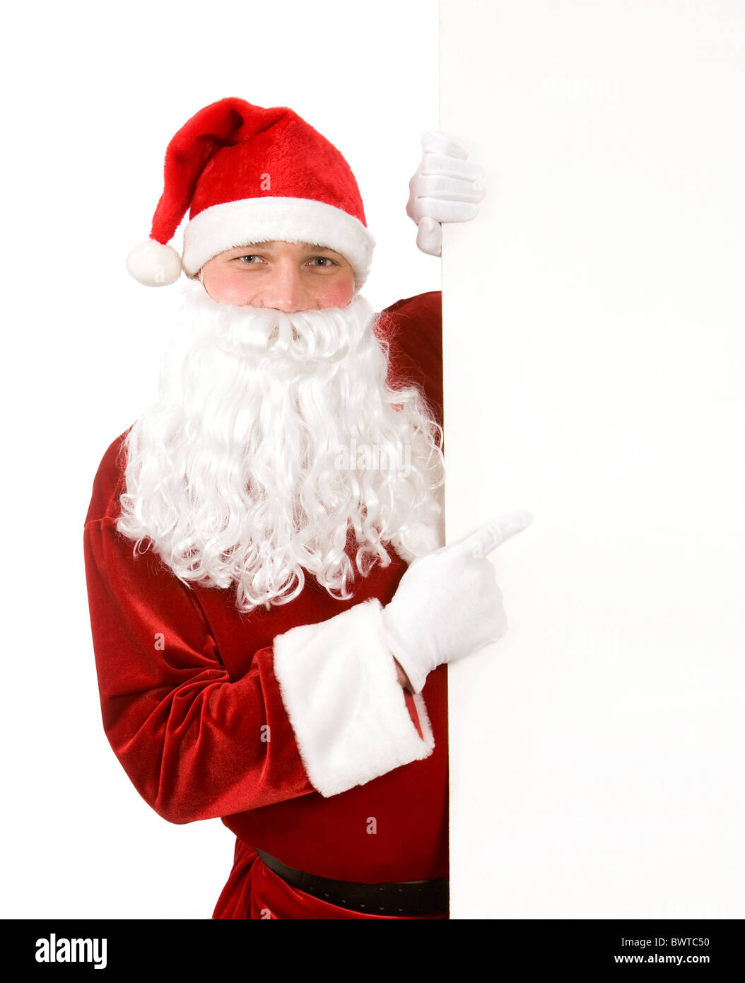 Photo of happy Santa Claus looking out of blank board and pointing at ...