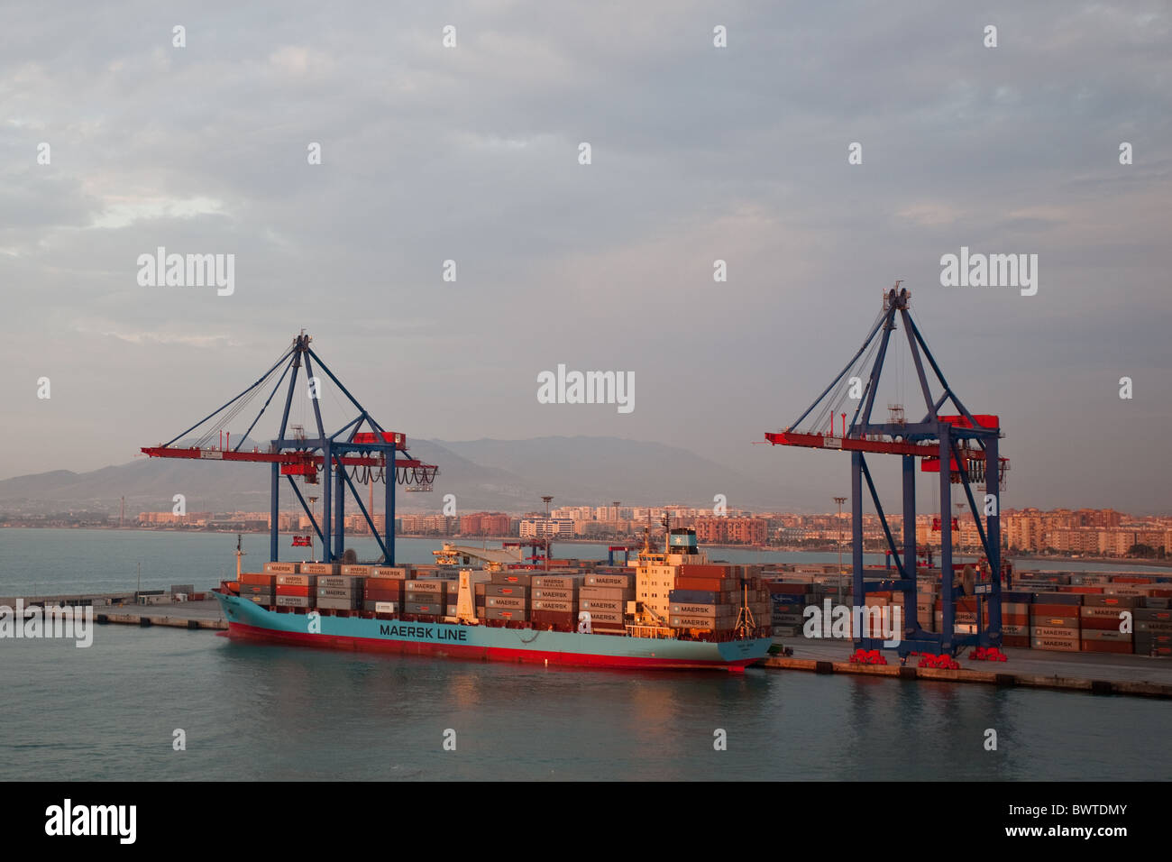 Dawn at Malaga harbour. Maersk container ship alongside harbour quay. Stock Photo