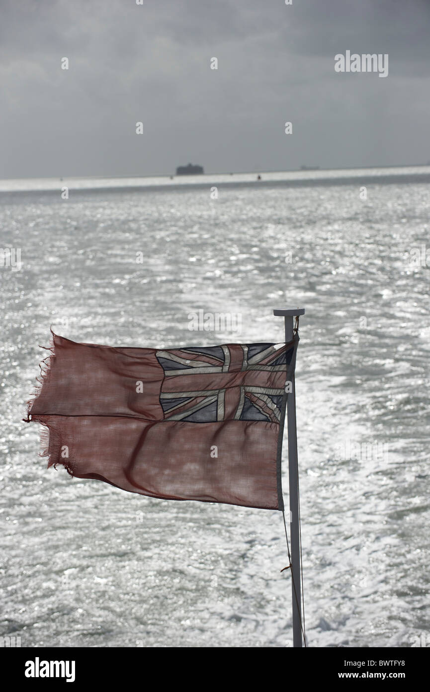 A tattered British flag flaps in the seabreeze on the ferry from the Isle of Wight to Portsmouth the day after Bestival 2010 on Stock Photo