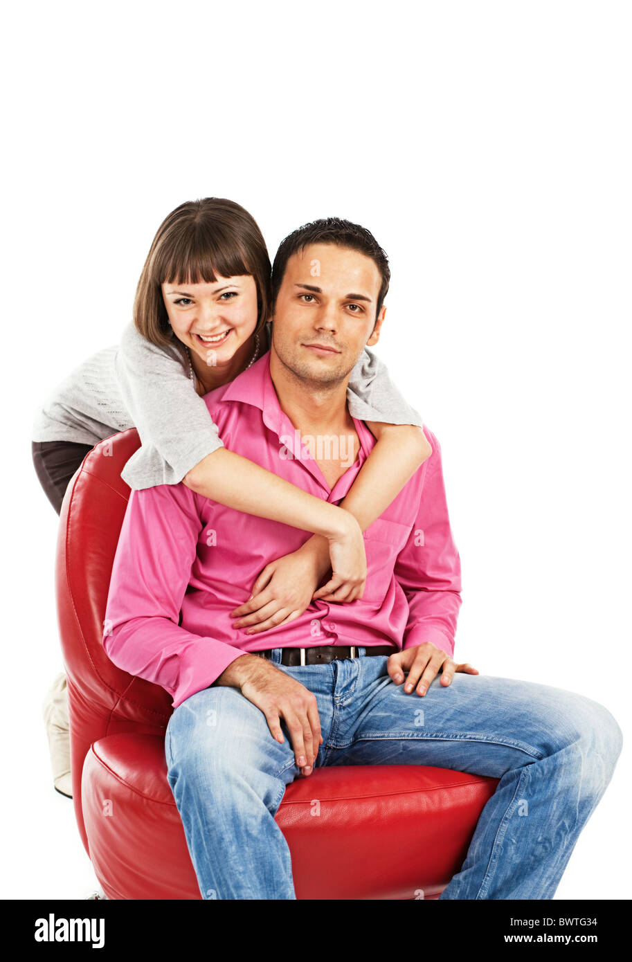 Happy young woman embraces man sitting on red leather chair Stock Photo