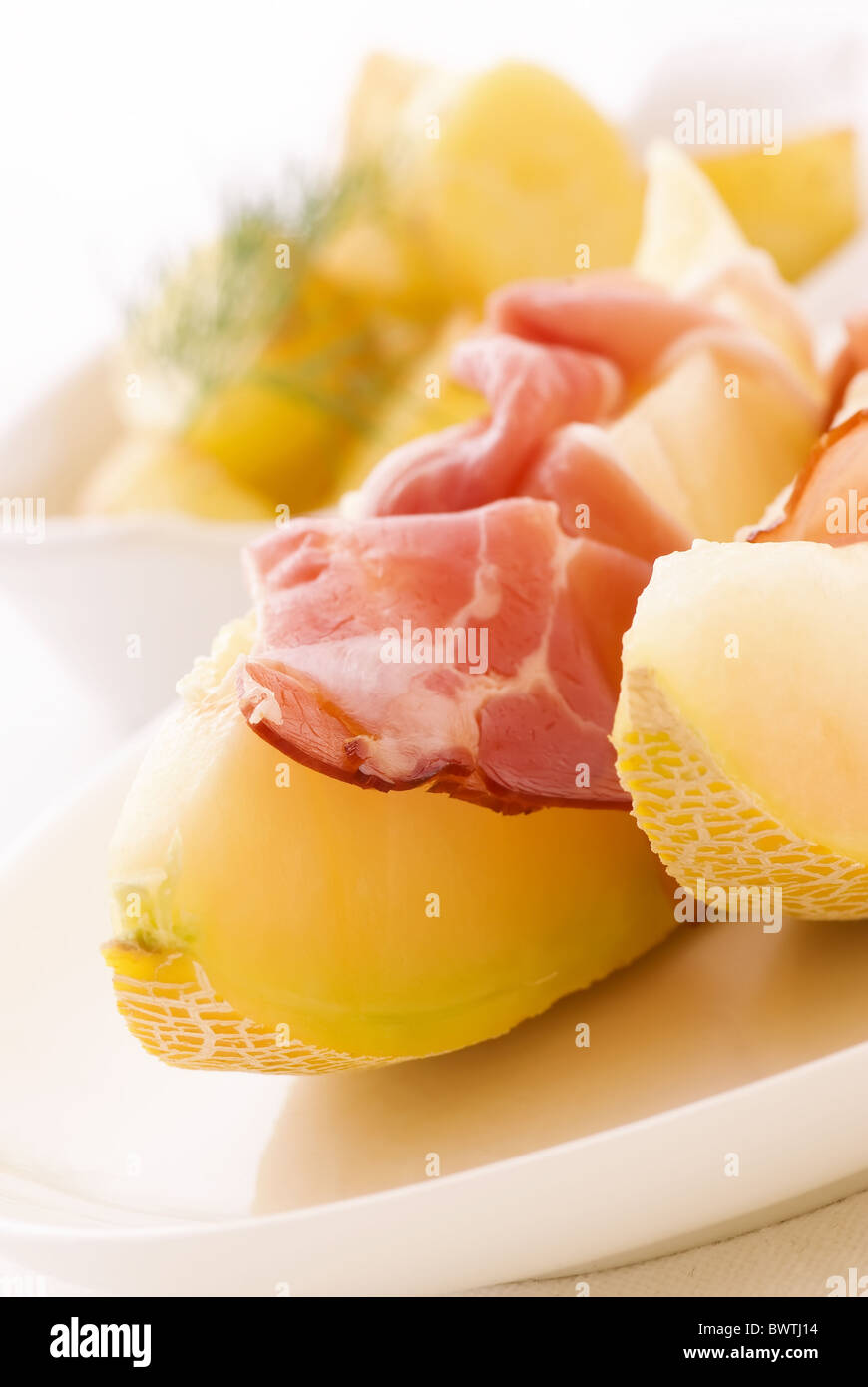 Rock melon with gammon and potatos as closeup on a white plate Stock Photo