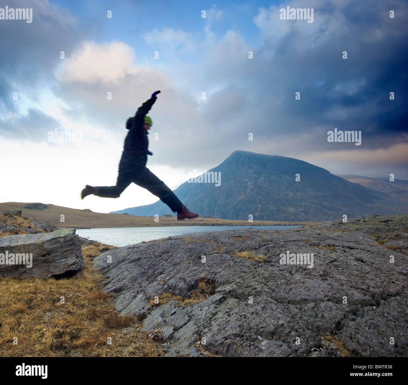 Walk Over Rocks Hiker jumping across rocks Llyn Idwal, by footpath to Devils Kitchen ...
