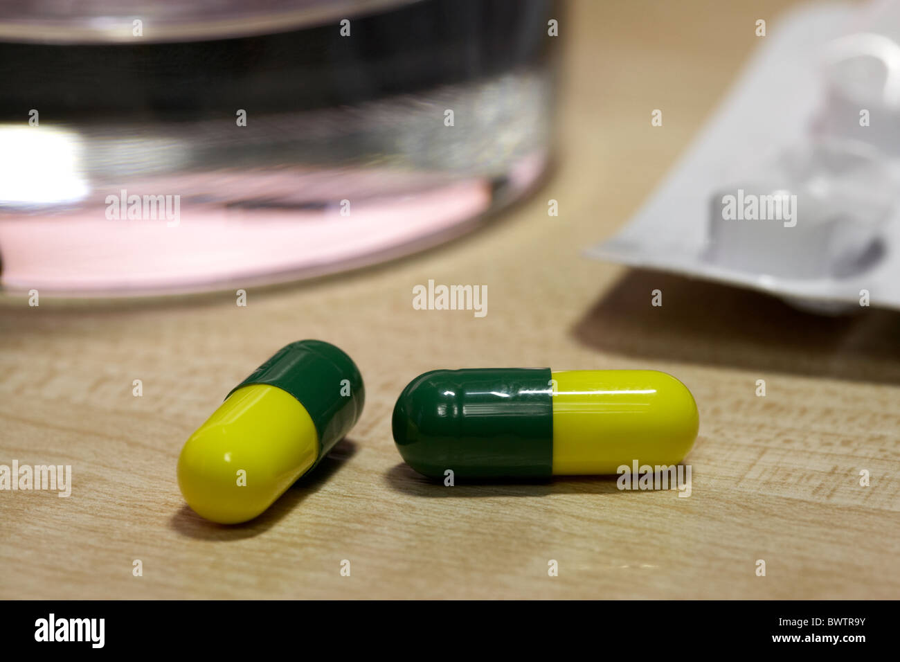 cold and flu remedy capsules with glass of water under artificial office lighting Stock Photo