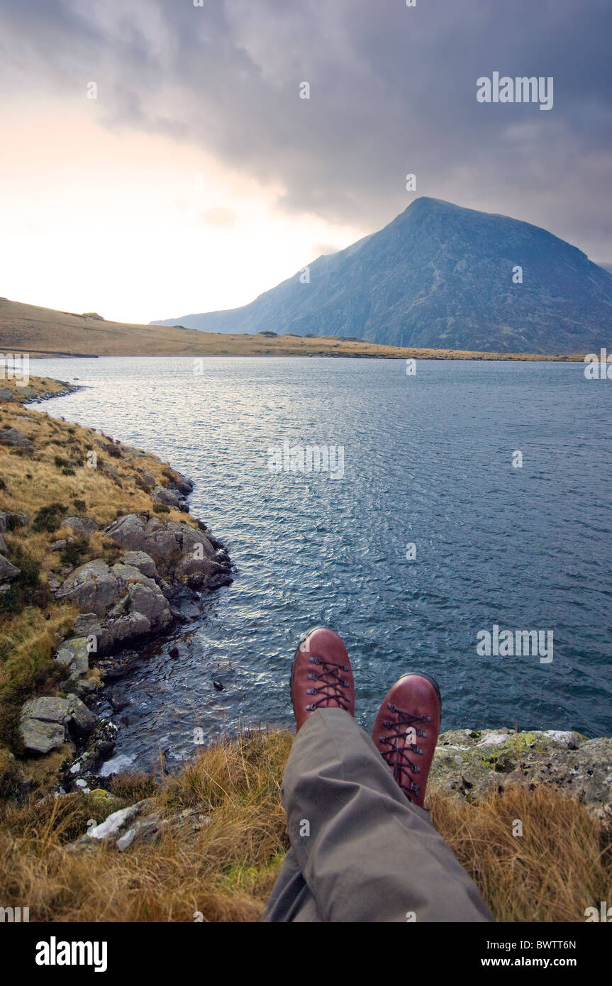 Hiker taking a rest near Llyn Idwal, by the footpath to Devils Kitchen, Snowdonia, North Wales. Pen yr Ole Wen  in the distance Stock Photo