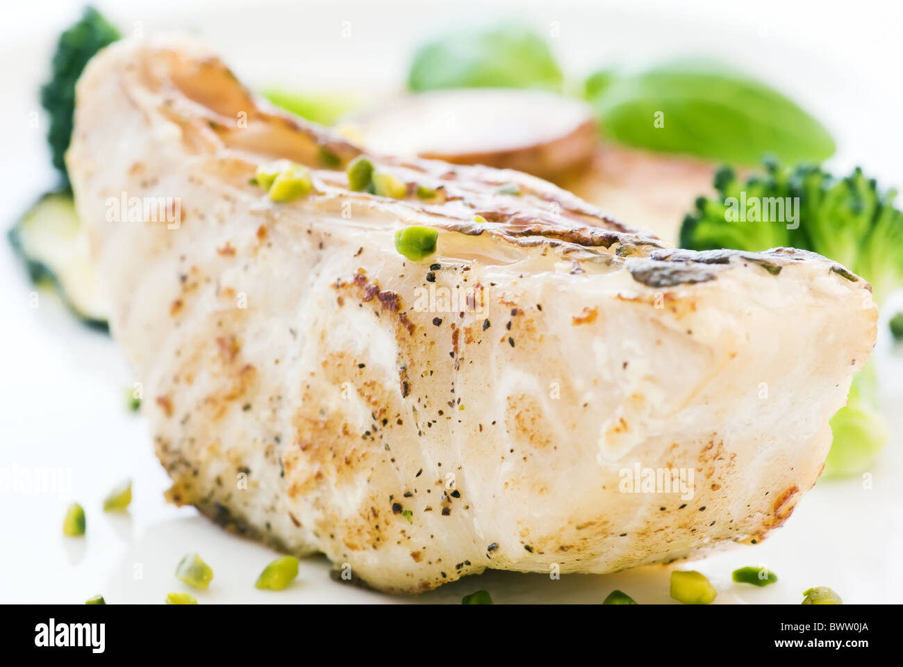 Parrot fish steak with vegetables and chips as closeup on a white plate Stock Photo