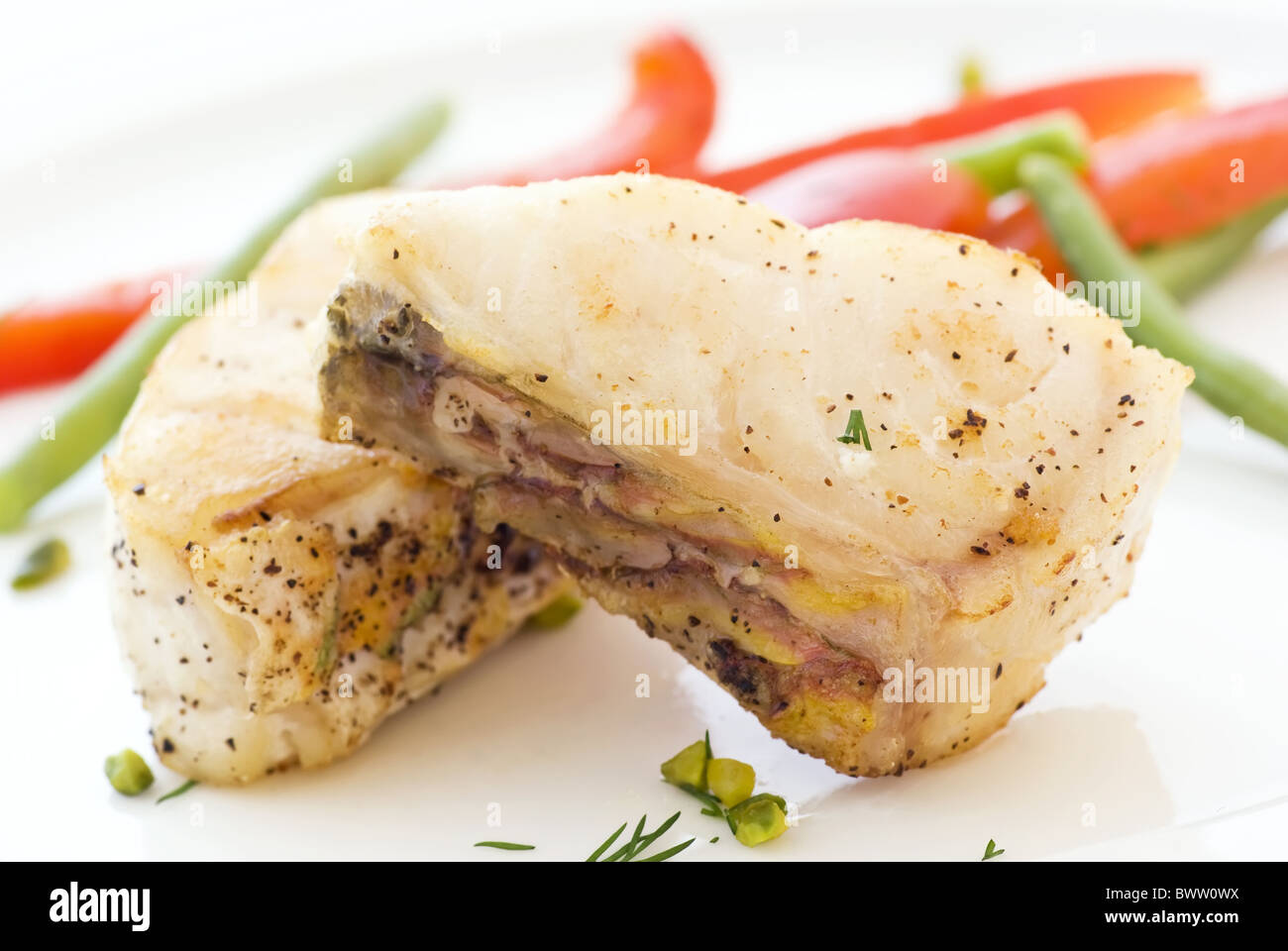 Parrot fish steak with vegetables as closeup on a white plate Stock Photo
