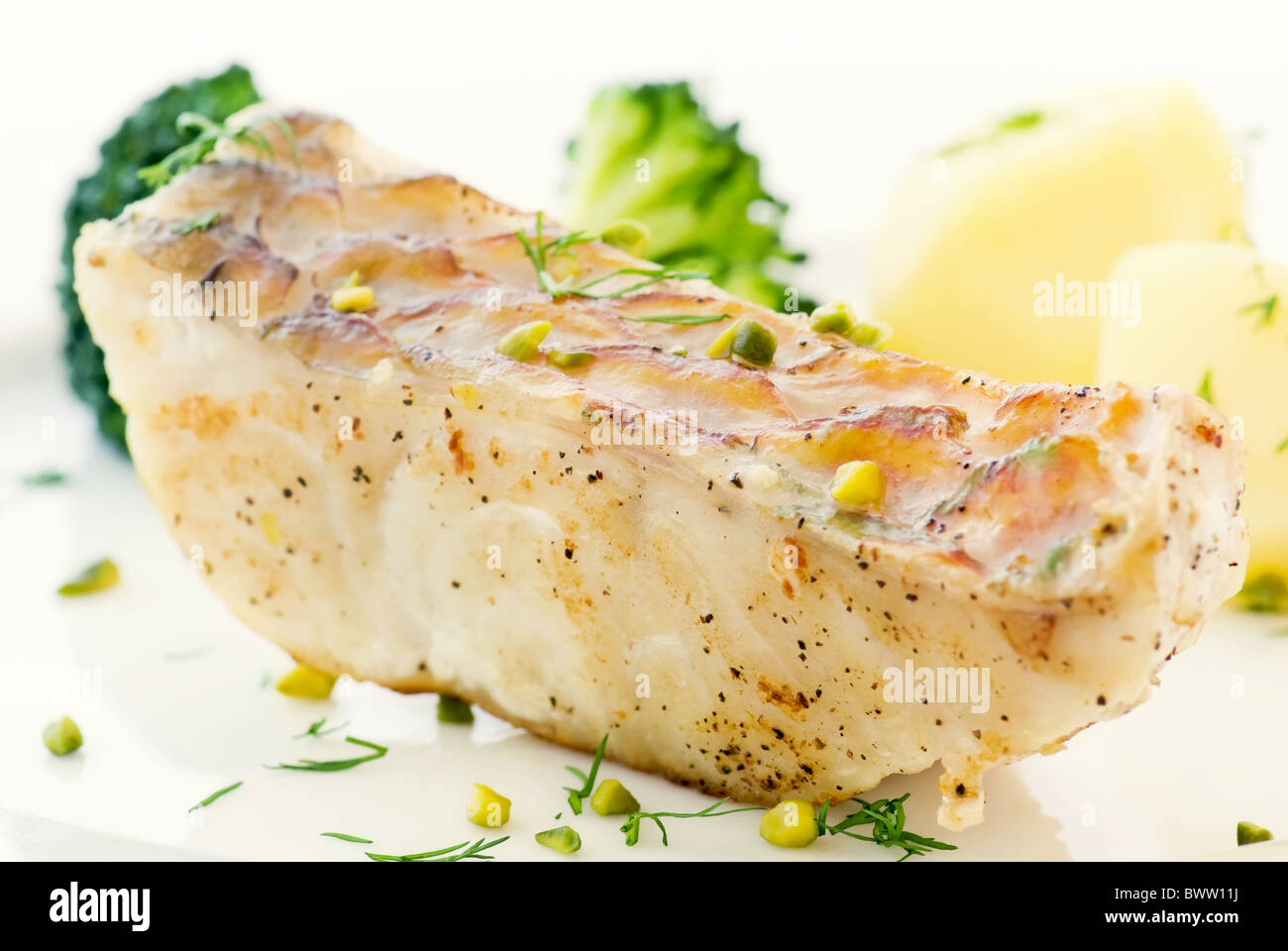 Parrot fish steak with vegetables and chips as closeup on a white plate Stock Photo