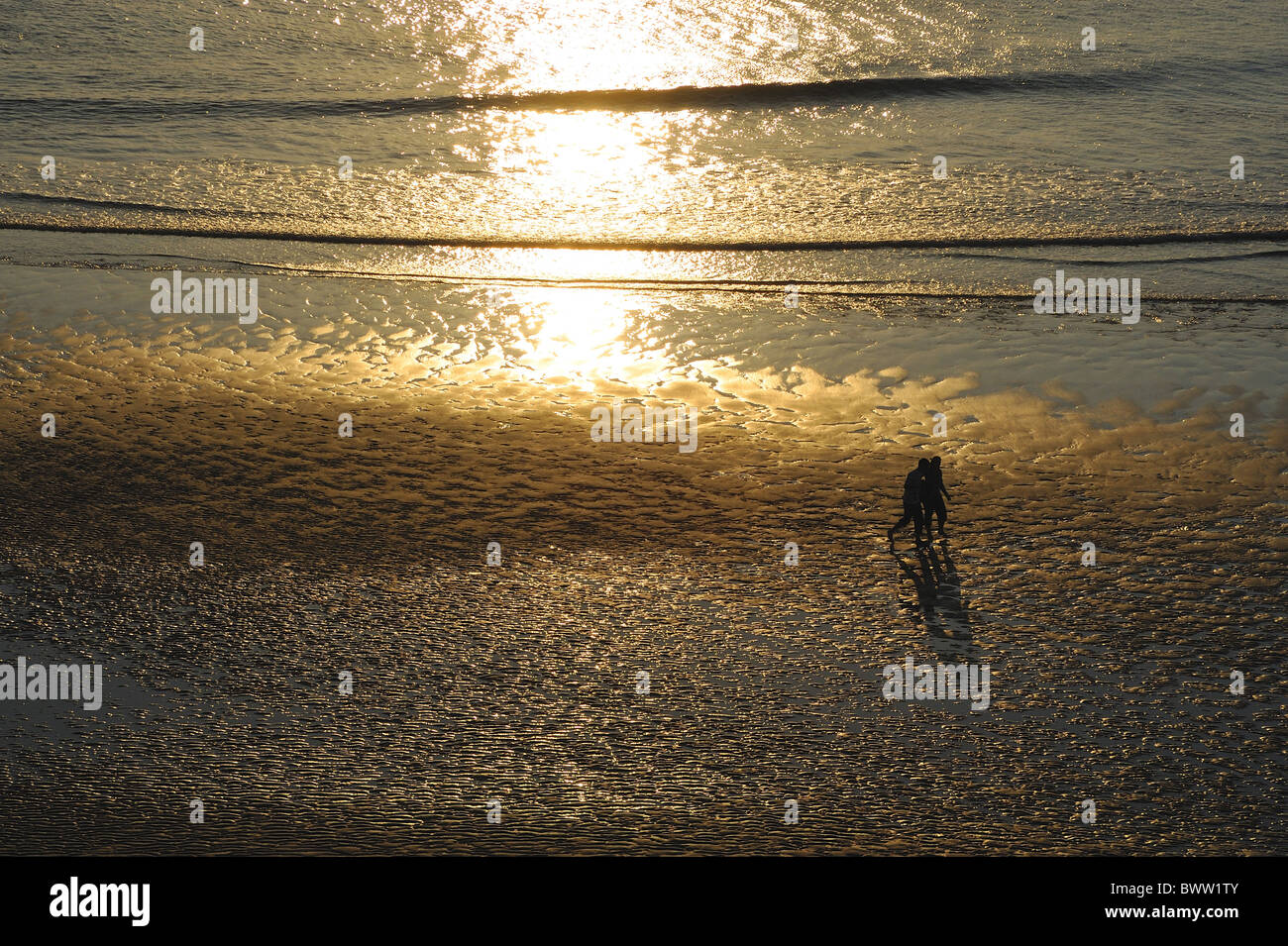 Two people walking along beach sunset Perranporth Stock Photo - Alamy