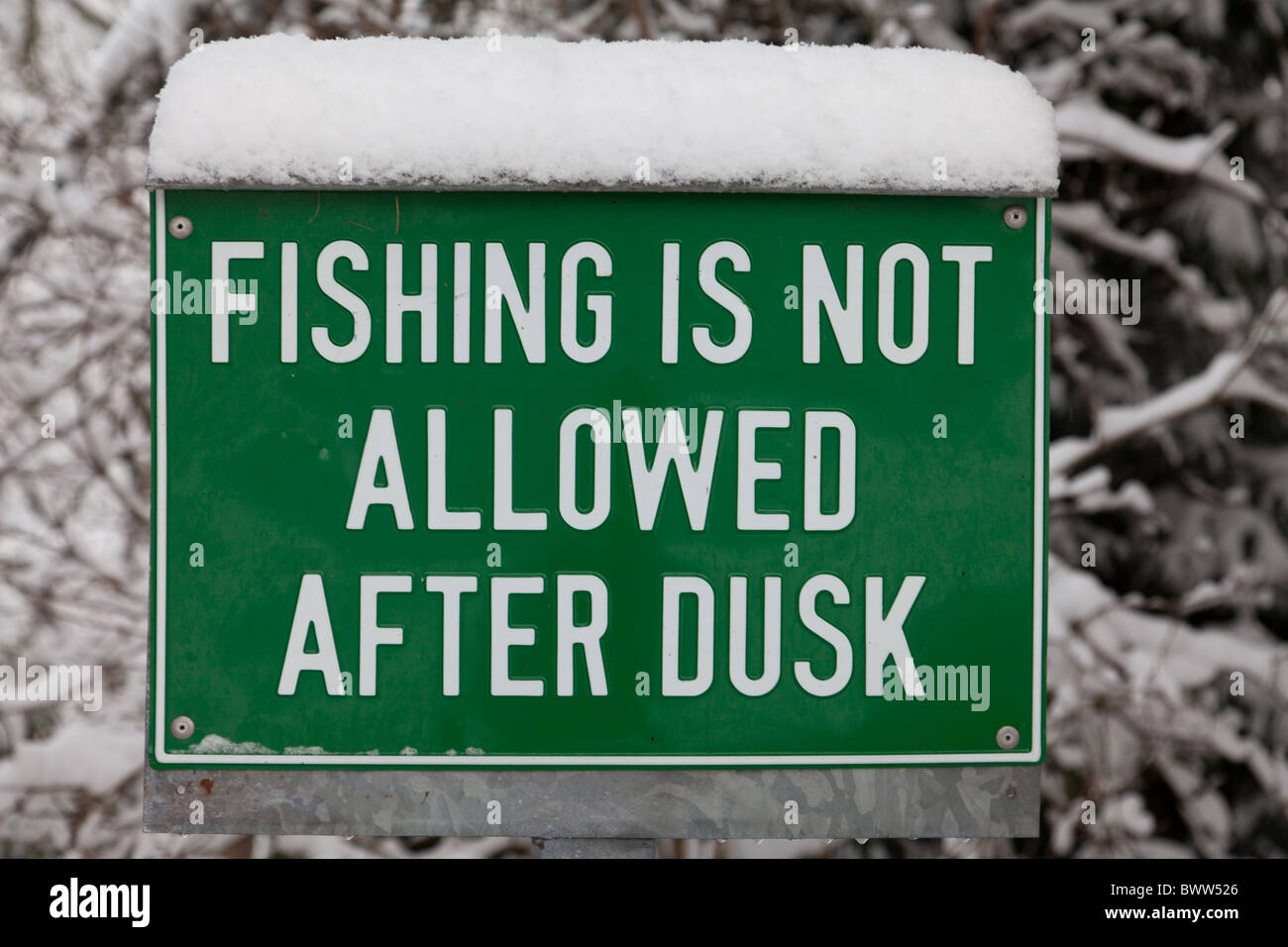 Fishing is not allowed after dusk sign by wire mill dam in Sheffield in winter. Stock Photo
