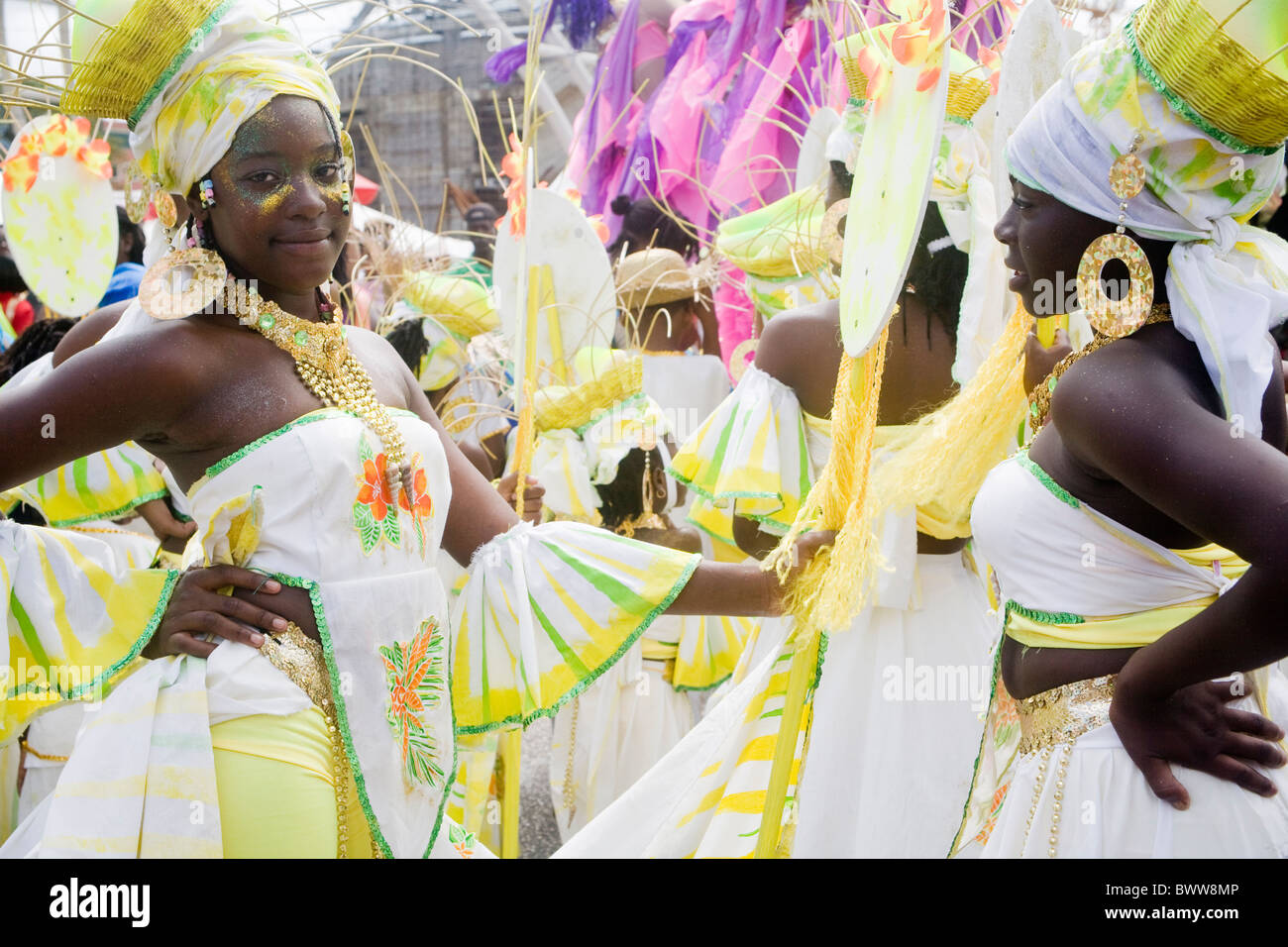 Trinidad Carnival - Two girls with hands on hips in floral white and yellow costume, baskets on their heads Stock Photo