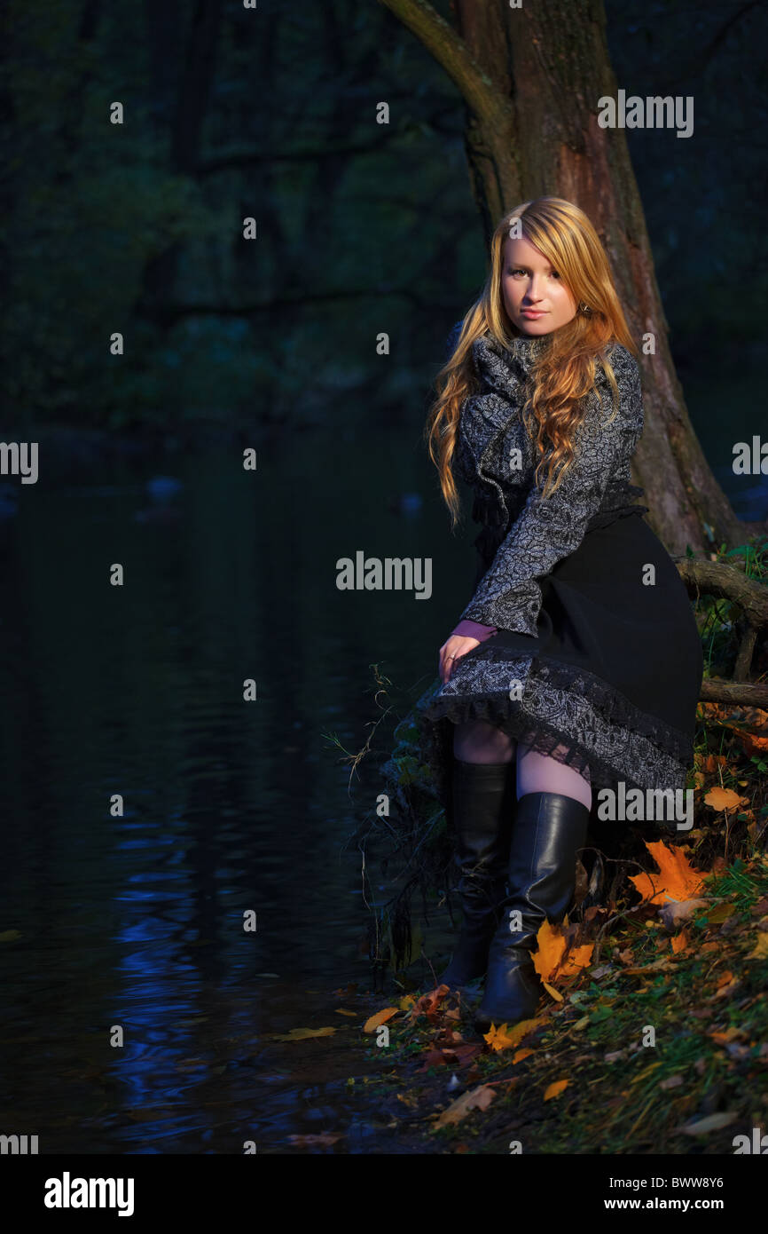 girl sitting on the edge of pond at evening Stock Photo Alamy