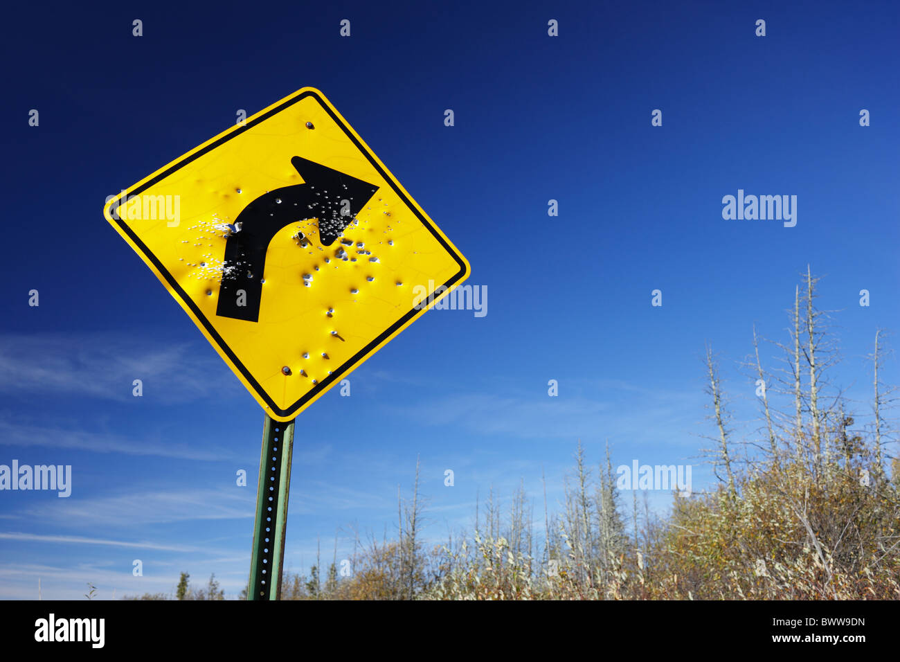 A shotgun blasted curve sign in a rural setting. Stock Photo