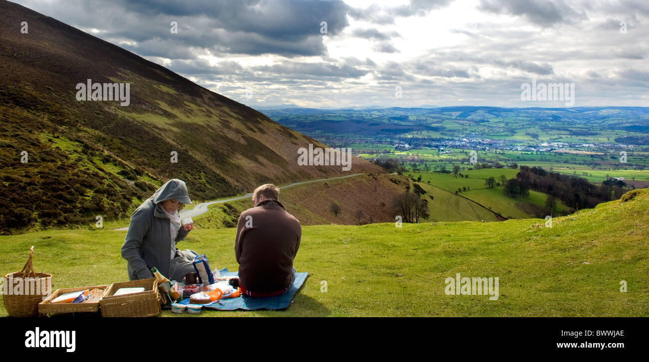 Couple share a picnic on Offas Dyke path with view of the market town Ruthin and the Vale of Clwyd. North Wales UK Stock Photo